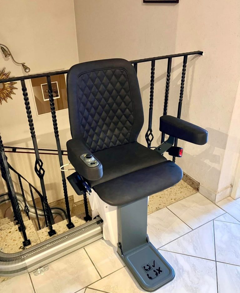 Treppenlift mit gepolsterter Sitzfläche und Armlehnen an einem Geländer montiert.